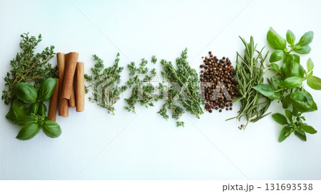 Basil, cinnamon sticks, thyme, peppercorns, and rosemary are lined up on a white surface. Concept of natural flavor and aroma. For cooking or culinary inspiration. 131693538