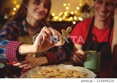 Family Friends Baking Christmas Cookies: Holding A Gingerbread Man In A Cozy Kitchen With Holiday Lights Family Friends Baking Christmas Cookies: Holding A Gingerbread Man In A Cozy Kitchen With Holiday Lights 131694228