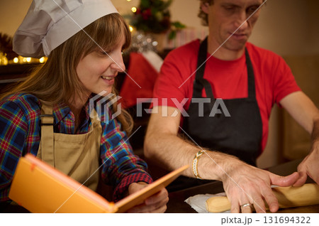 Joyful Holiday Baking Scene With A Chef Hat And Apron As Friends Prepare Dough In A Warm Kitchen For Christmas Or Family Gathering Joyful Holiday Baking Scene With A Chef Hat And Apron As Friends Prepare Dough In A Warm Kitchen For Christmas Or Family Gathering 131694322