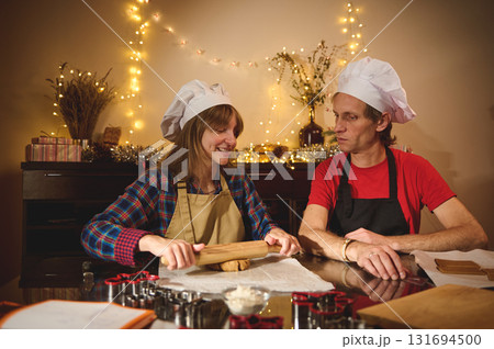 Two Chefs Bake Christmas Cookies Together in Cozy Kitchen Decorated with Fairy Lights Two Chefs Bake Christmas Cookies Together in Cozy Kitchen Decorated with Fairy Lights 131694500