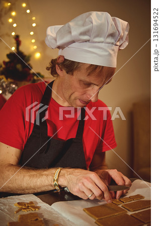 Chef at Work: Christmas Baking Scene with White Hat, Red Shirt, and Warm Fairy Lights in the Background Chef at Work: Christmas Baking Scene with White Hat, Red Shirt, and Warm Fairy Lights in the Background 131694522