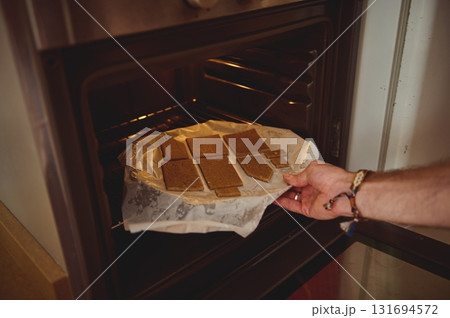 Candid Kitchen Moment: A Hand Places Brownies on Parchment Tray After Baking From the Oven 131694572