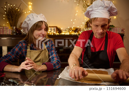 Bakers in Chef Hats Rolling Dough Together in a Cozy Kitchen 131694600