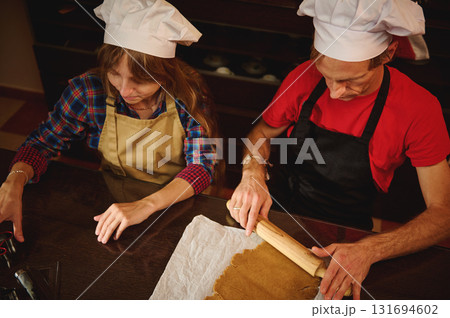 Two Chefs At Counter Rolling Dough In Kitchen, Preparing Fresh Pastry Together Two Chefs At Counter Rolling Dough In Kitchen, Preparing Fresh Pastry Together 131694602