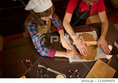 Two People Baking Gingerbread Cookies At The Kitchen Table With Rolling Pin And Cookie Cutters Two People Baking Gingerbread Cookies At The Kitchen Table With Rolling Pin And Cookie Cutters 131694603