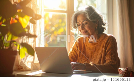 朝の光の中で副業する主婦の写真｜在宅ワーク・家庭・ノートパソコン 131696112