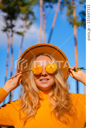 Woman faceless yellow sweater closing eyes with orange dahlia into camera Autumn Fall Bouquet for Thanksgiving holiday. Seasonal Warm colorful blossom flowers arrangement festive decoration 131697331