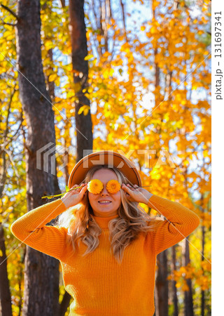 Woman in yellow sweater close her eyes with yellow dahlia Selective focus Bush of autumnal orange red chrysanthemums and violet dahlia hydrangea. Fall garden beautiful flowers bouquet background 131697341