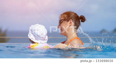Mother and daughter swimming in infinity pool Mother and daughter swimming in infinity pool 131698010