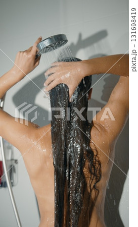 A woman showers with her long hair flowing, enjoying a refreshing moment of beauty and care A woman showers with her long hair flowing, enjoying a refreshing moment of beauty and care 131698419
