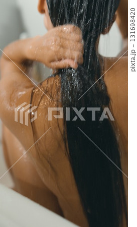 A woman washes her hair in a peaceful bath, surrounded by flowing water and a tranquil ambiance 131698420