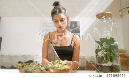 A woman is deeply engaged in caring for her plants and tending to her beautiful garden A woman is deeply engaged in caring for her plants and tending to her beautiful garden 131698433