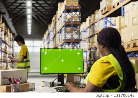 Warehouse worker in a hi-vis vest uses copy space display with technology of shipping software, packaging systems and inventory management tools. automation in e-commerce logistics. 131700148