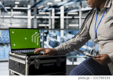 Mockup laptop next to female engineer in server hub implementing data backup and recovery solutions. African american data center employee using green screen notebook, optimizing network management Mockup laptop next to female engineer in server hub implementing data backup and recovery solutions. African american data center employee using green screen notebook, optimizing network management 131700193