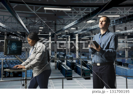 Server farm team of technicians using devices to do infrastructure AI machine learning automatization. Data center programmer and coworker doing maintenance using artificial intelligence Server farm team of technicians using devices to do infrastructure AI machine learning automatization. Data center programmer and coworker doing maintenance using artificial intelligence 131700195
