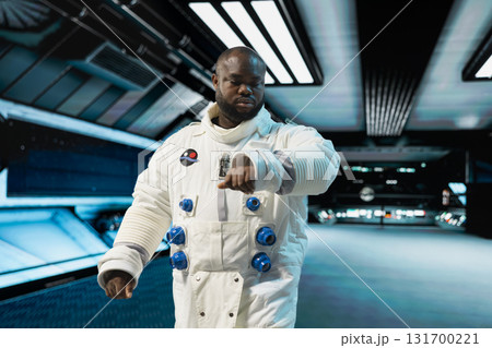 Astronaut in spaceship looking at wrist device to confirm suit integrity, preparing for planetary mission outside. Orbital station crew member testing gear during routine equipment check Astronaut in spaceship looking at wrist device to confirm suit integrity, preparing for planetary mission outside. Orbital station crew member testing gear during routine equipment check 131700221