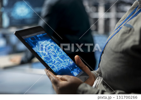 Close up of tablet used by data center computer scientist to upgrade storage devices for minimal latency in AI workloads. IT specialist using device in high tech server hub to build neural networks Close up of tablet used by data center computer scientist to upgrade storage devices for minimal latency in AI workloads. IT specialist using device in high tech server hub to build neural networks 131700266