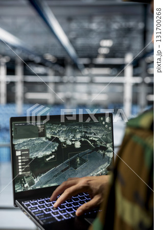 Close up of army expert in data center supporting mission operations with aerial surveillance tools. Military man in server room checking ballistic missiles movement on reconnaissance feed Close up of army expert in data center supporting mission operations with aerial surveillance tools. Military man in server room checking ballistic missiles movement on reconnaissance feed 131700268