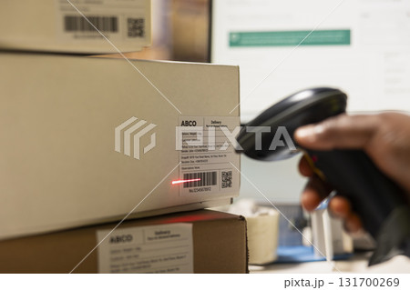 Close up of black employee scanning airway bill tags barcodes, registering the shipping labels numbers in the package tracking software. Using scanner to help later with inventory in depot. 131700269