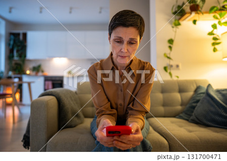 Sad apathetic mature woman waiting for news, checking smartphone notifications alone at home 131700471