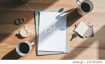Cozy Workspace with Blank Papers, Coffee Cups, Keys, Color Swatches and Natural Light Shadows 131701914