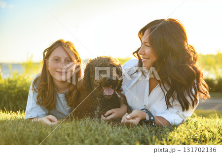 brown portuguese water dog outdoors on grass with mother and daughter brown portuguese water dog outdoors on grass with mother and daughter 131702136