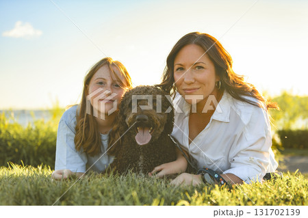 brown portuguese water dog outdoors on grass with mother and daughter brown portuguese water dog outdoors on grass with mother and daughter 131702139