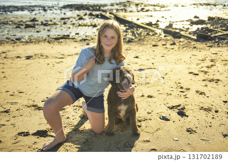Portrait of one brown portuguese water dog outdoors on the beach with little child girl 131702189