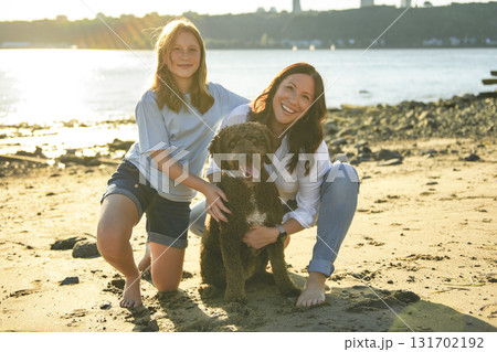 brown portuguese water dog outdoors on the beach with mother and daughter brown portuguese water dog outdoors on the beach with mother and daughter 131702192