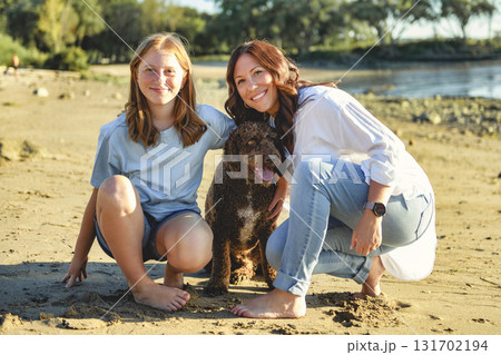 brown portuguese water dog outdoors on the beach with mother and daughter brown portuguese water dog outdoors on the beach with mother and daughter 131702194
