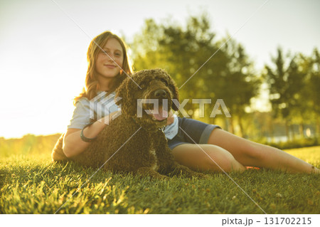 Portrait of one brown portuguese water dog outdoors on grass with little child girl 131702215