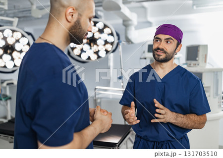 Two surgeons are seen in an operating room, engaged in a discussion, likely planning or reviewing a procedure. 131703510
