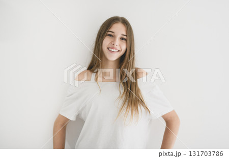 Portrait of teenage girl in casual t-shirt on light background in studio. Portrait of teenage girl in casual t-shirt on light background in studio. 131703786