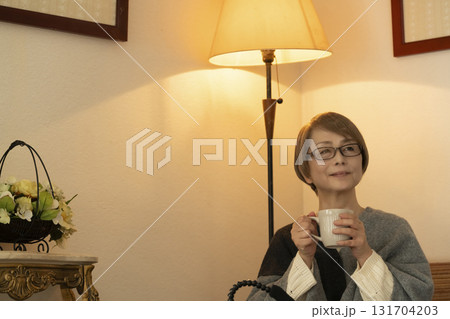 湯気の立った温かい飲み物をリビングで飲むシニア女性 131704203
