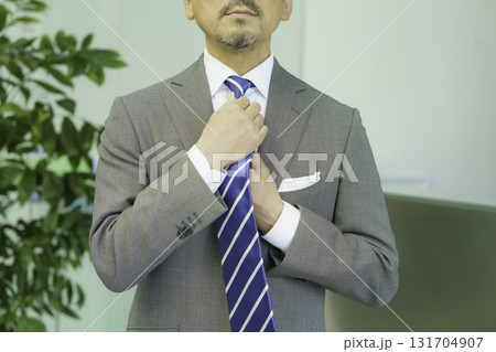 ミドルエイジの男性のネクタイを直す手元のアップ　撮影協力:スカパー東京メディアセンター 131704907