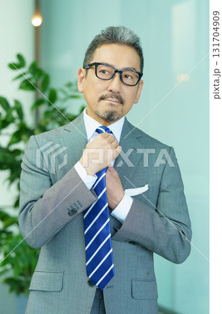 ネクタイを治すミドルエイジの男性　縦位置　撮影協力:スカパー東京メディアセンター 131704909