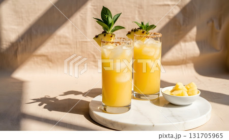 Refreshing tropical cocktails with pineapple garnish on a sunny table setting 131705965
