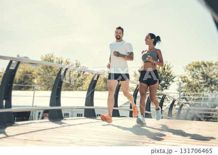 Young fitness couple running on a city on summer day Young fitness couple running on a city on summer day 131706465