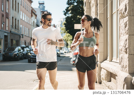 Young fitness couple running on a city on summer day Young fitness couple running on a city on summer day 131706476