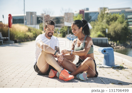 Young fitness couple sporty sit and watching watch on a city on summer day Young fitness couple sporty sit and watching watch on a city on summer day 131706499