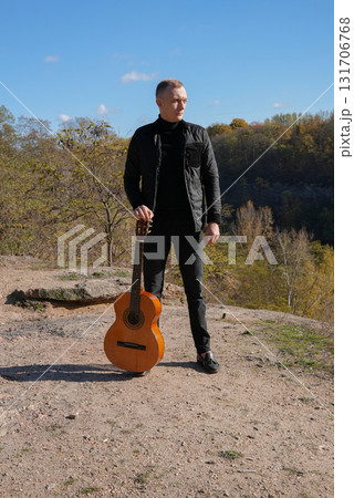 Blonde man playing string guitar outdoors in autumn forest. Concept of sound therapy, mental health and wellness rituals. Calmness tranquility audio-sensory practices. Aura farming energy Blonde man playing string guitar outdoors in autumn forest. Concept of sound therapy, mental health and wellness rituals. Calmness tranquility audio-sensory practices. Aura farming energy 131706768
