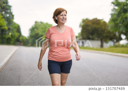 Woman fast walking outdoors with wireless headphones 131707489