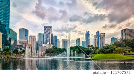 Panoramic view of Kuala Lumpur city center, Malaysia, with contemporary skyscrapers, KLCC park lake, fountains, lush greenery, dramatic evening sky, architectural landmarks. Reflection cityscape in 131707573