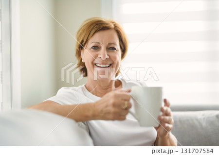 mature woman drink coffee on sofa at home 131707584