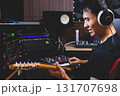 smiling asian male music producer, musician, guitarist, artist playing and recording electric guitar in home studio. recording concept 131707698
