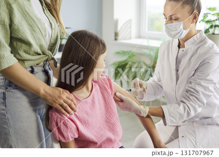 Pediatric clinic vaccination: doctor gives child an injection while parent helps 131707967