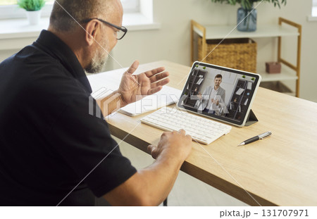Mature man on video call during online meeting, tablet on desk for coaching 131707971
