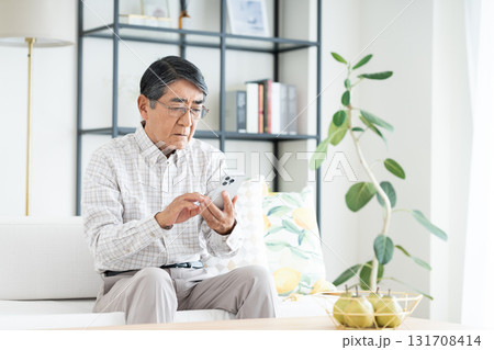 リビングでスマホを使うシニアの男性 リビングでスマホを使うシニアの男性 131708414