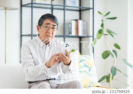 リビングでスマホを使うシニアの男性 リビングでスマホを使うシニアの男性 131708420