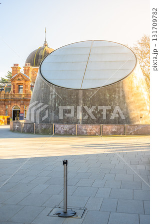 The Peter Harrison Planetarium stands prominently in Greenwich, London. Its modern design contrasts with the classic architecture nearby, welcoming visitors for learning and exploration. The Peter Harrison Planetarium stands prominently in Greenwich, London. Its modern design contrasts with the classic architecture nearby, welcoming visitors for learning and exploration. 131709782